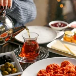 Yağmur sabah kahvaltısı: çay, zeytin, reçel ve peynirle dolu geleneksel Türk sofrası.